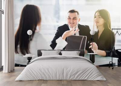 Young love couple sitting at a desk in the office of their agent or adviser discussing an investment presentation. Wall mural